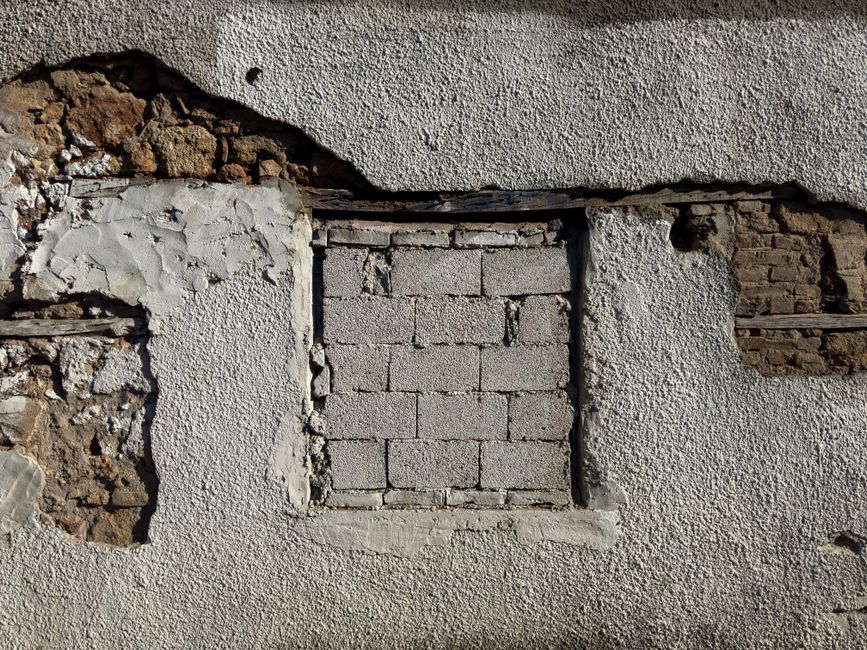 Close view of a historic brick and stone facade, the mortar joints and weathering patterns an assessment reads before any repair begins